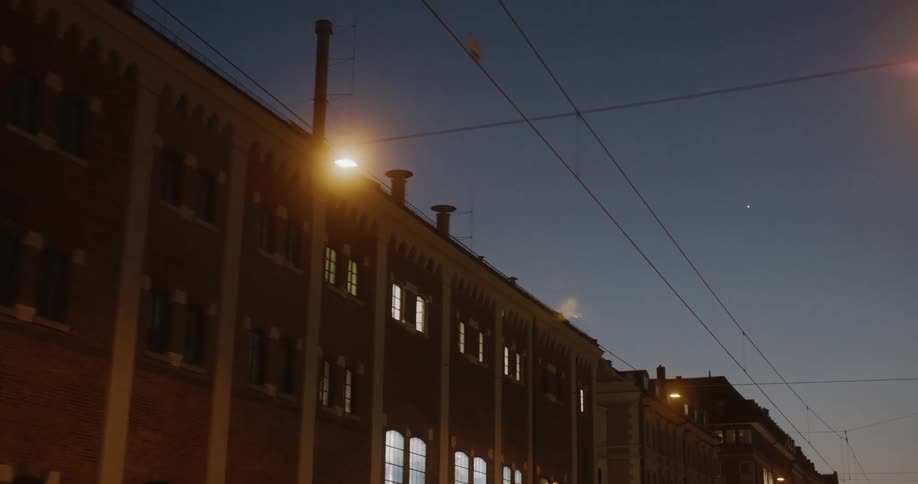 Power lines parallel the street and a large building during the evening