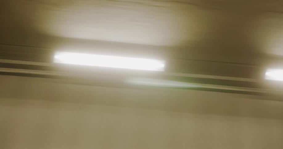 Long thin lights line the ceiling of a tunnel