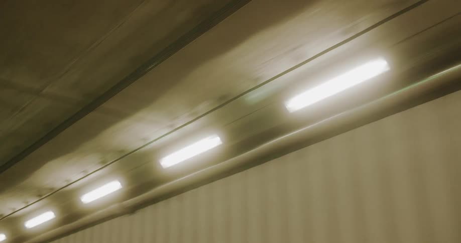Lighting near the ceiling of a tunnel with a fire alarm underneath