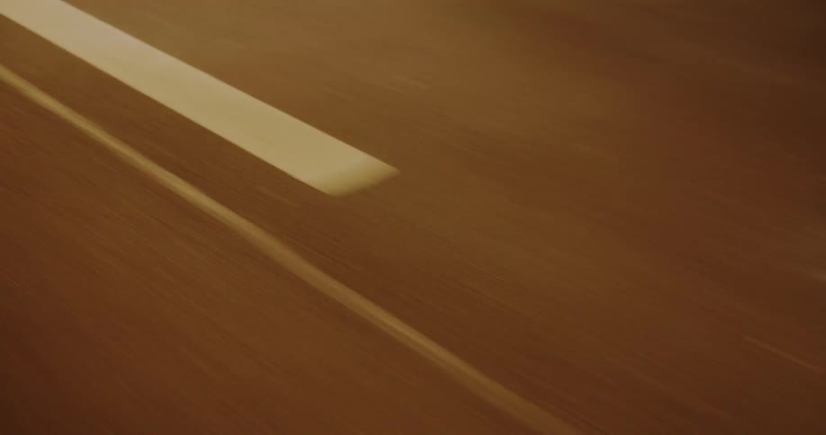 A car wheel and part of a white vehicle against a dark asphalt surface with a bright yellow line