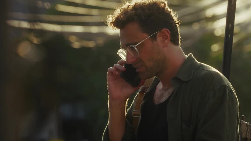 The man with the glasses is talking to someone on his cell phone