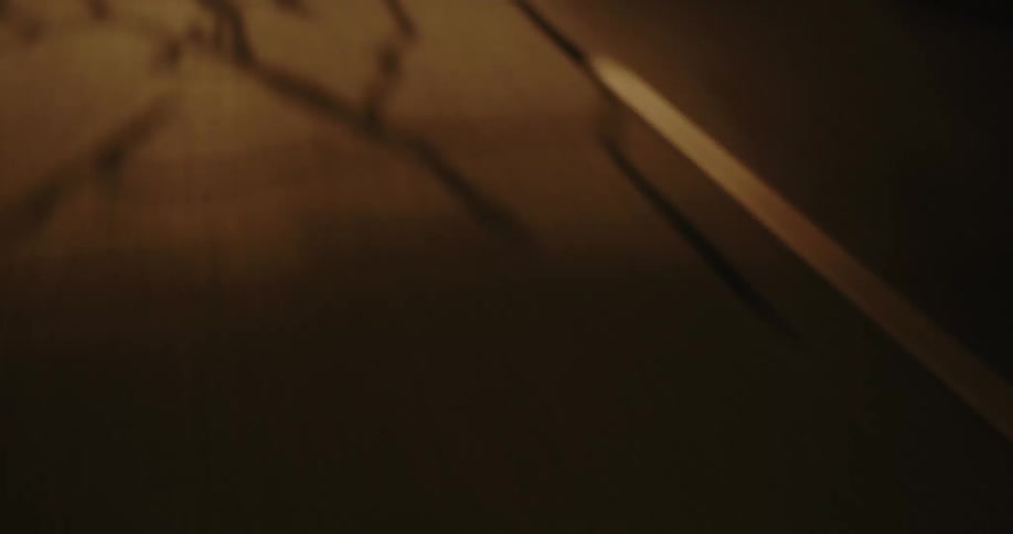 A dark road is illuminated by headlights showing a white dividing line curving into the distance