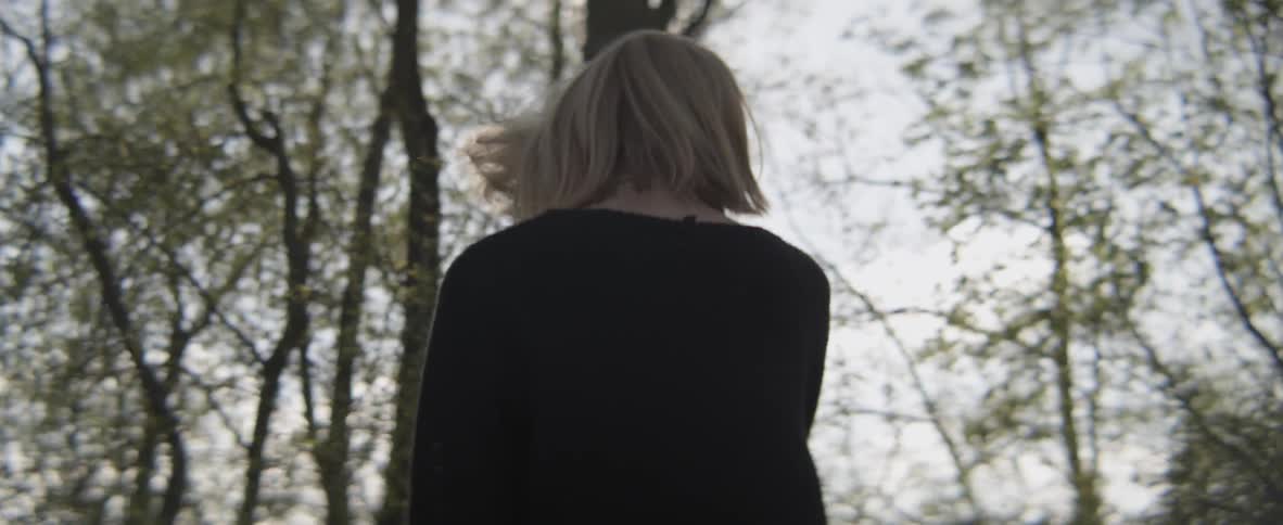 A woman turns around in the woods smiling