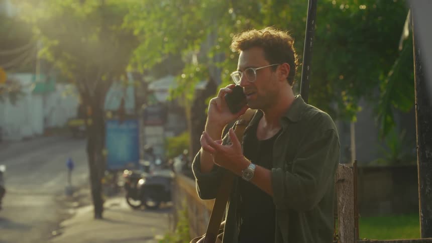 A man talks on his cell phone on the side of the road