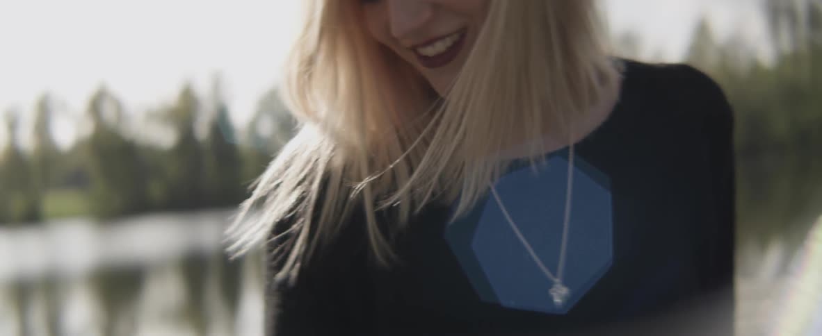 A woman standing outside near a lake is smiling