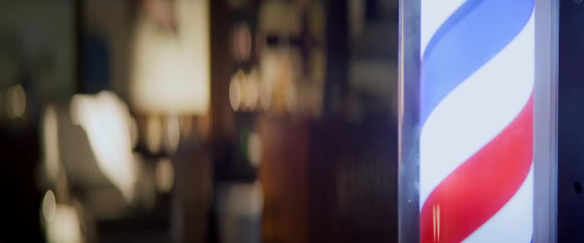 A barber pole lit sign spins in the barbershop