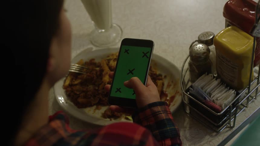 A woman uses her phone over her plate of food