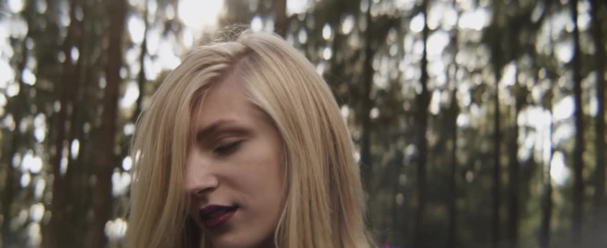 Woman with blond hair turns to look at trees