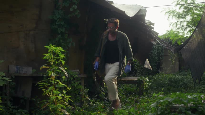 A man is walking past the shelter in the jungle