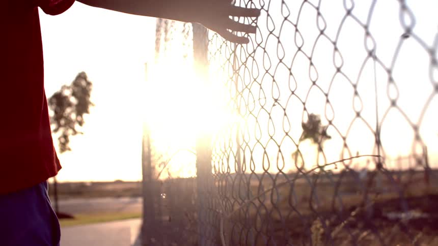 A kid walking past a fence