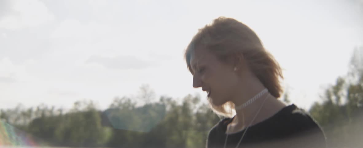 The wind blows a woman's hair on a sunny day
