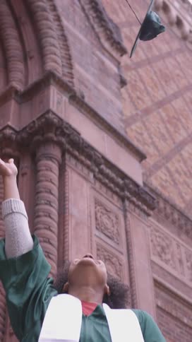 Valedictorian happily tossing cap in the air celebrating graduating