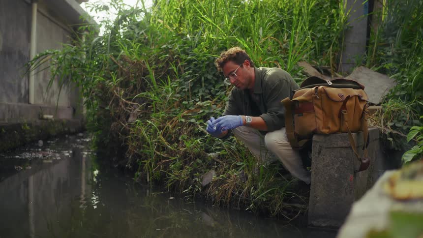A man collects a sample from an urban waterway