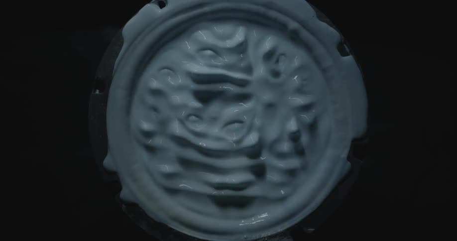 An overhead view of a can of paint shaking and the paint is bubbling