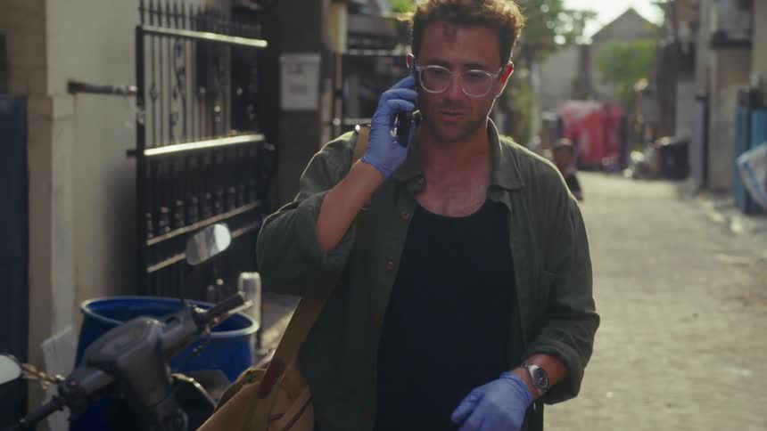 A man is walking through the alley and talking on his phone