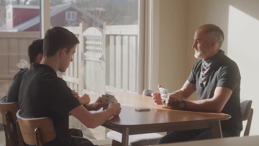A family of three are sitting at a table and playing a card game