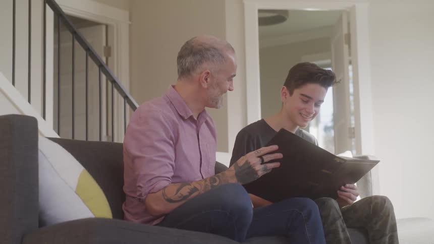 Father and son sitting on a sofa looking at a book