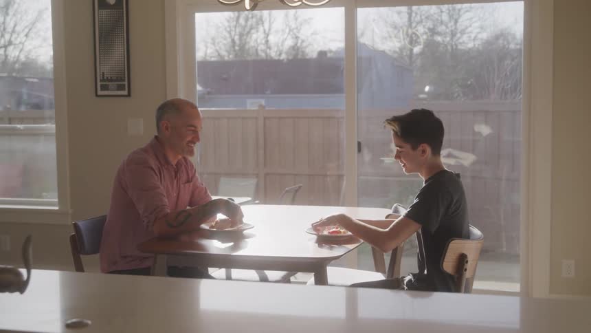 Father and son sitting at the table and starting to eat