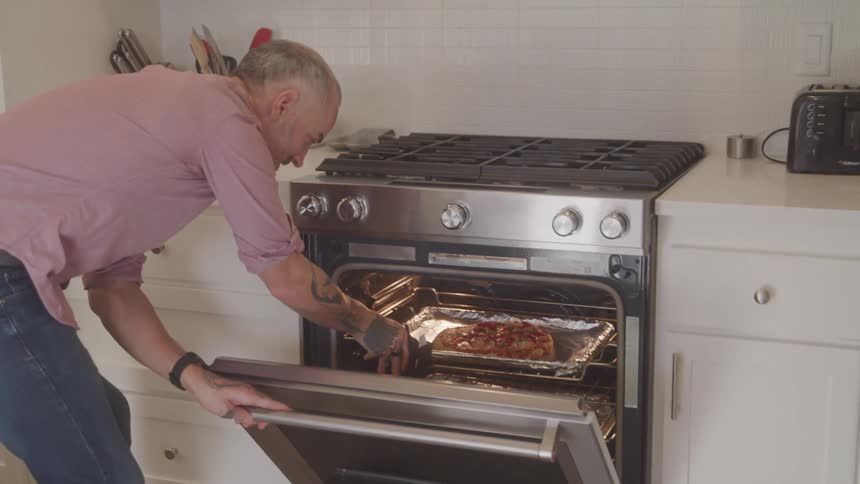 Man pulling a pan of food out of the oven