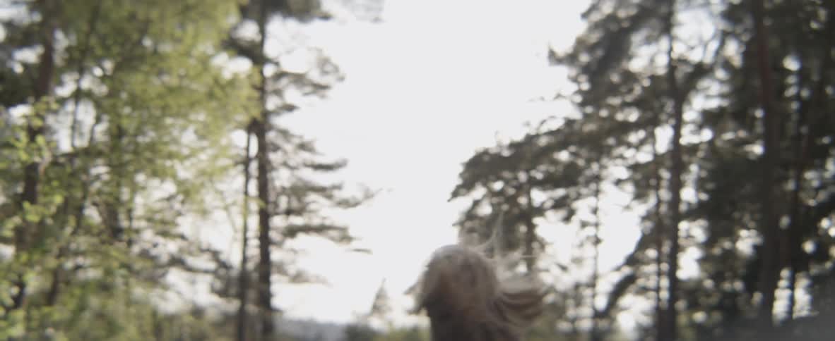 A woman is running through a forested area in daylight