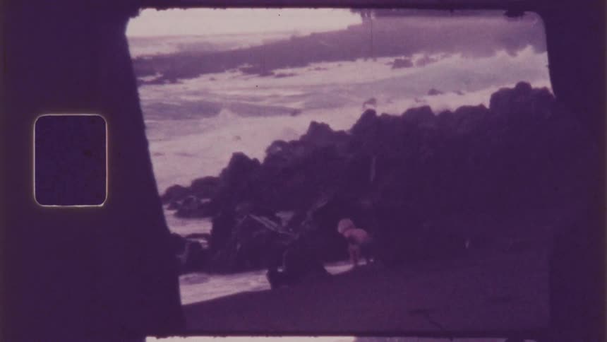 A boy is playing by the rocks on the beach