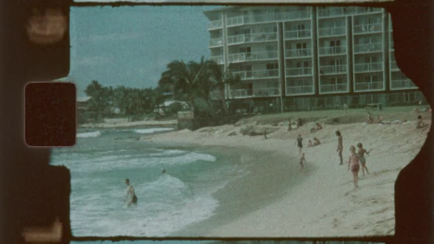 People enjoy themselves on the beach near a building on a sunny summer day