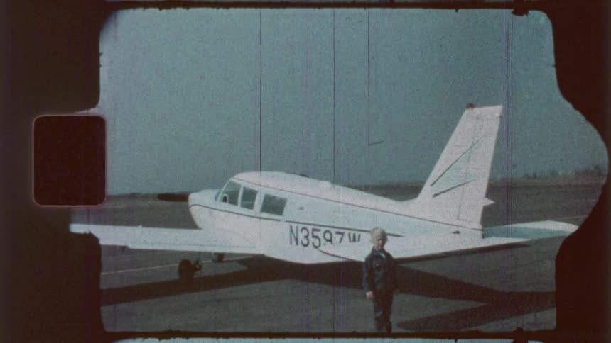 A boy is standing in front of a plane