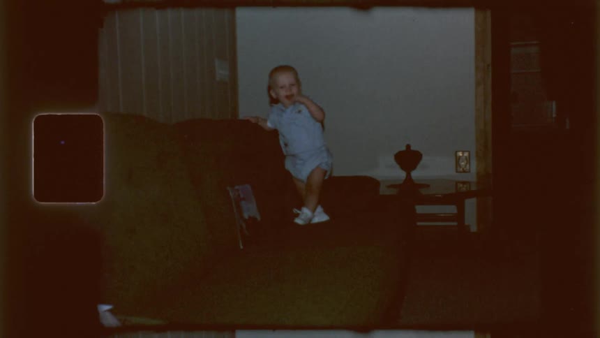The baby is standing on the couch