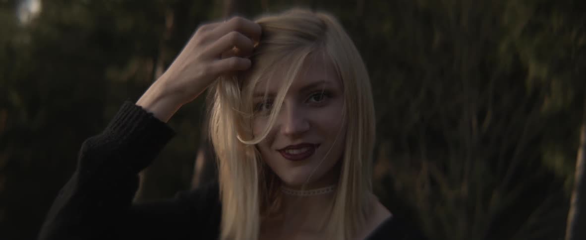A woman is brushing her hair to the side smiling