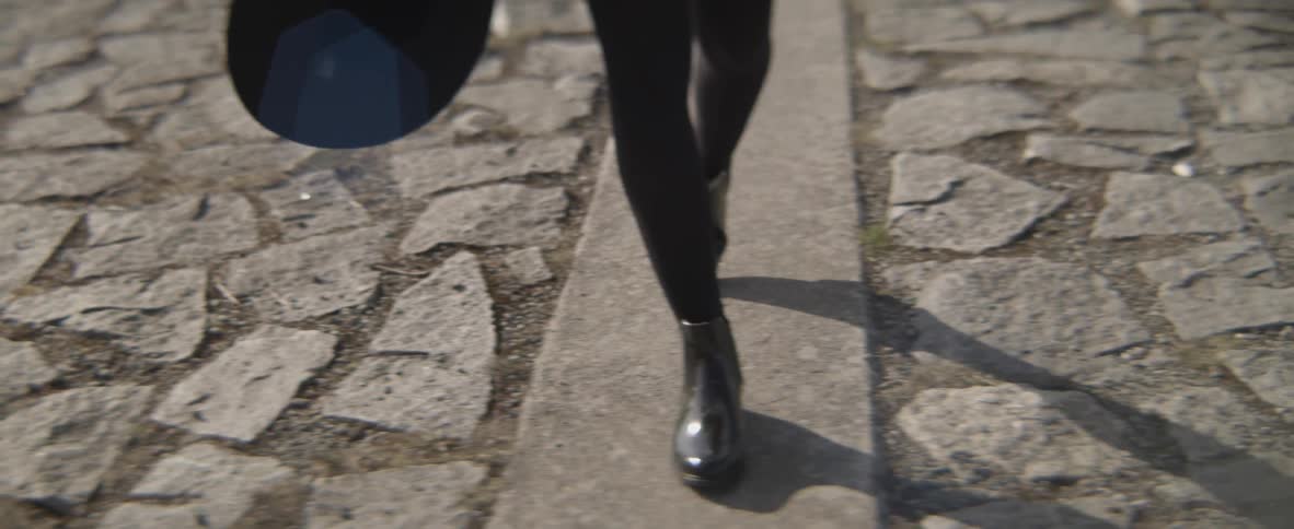 The legs and feet of a woman walking on concrete