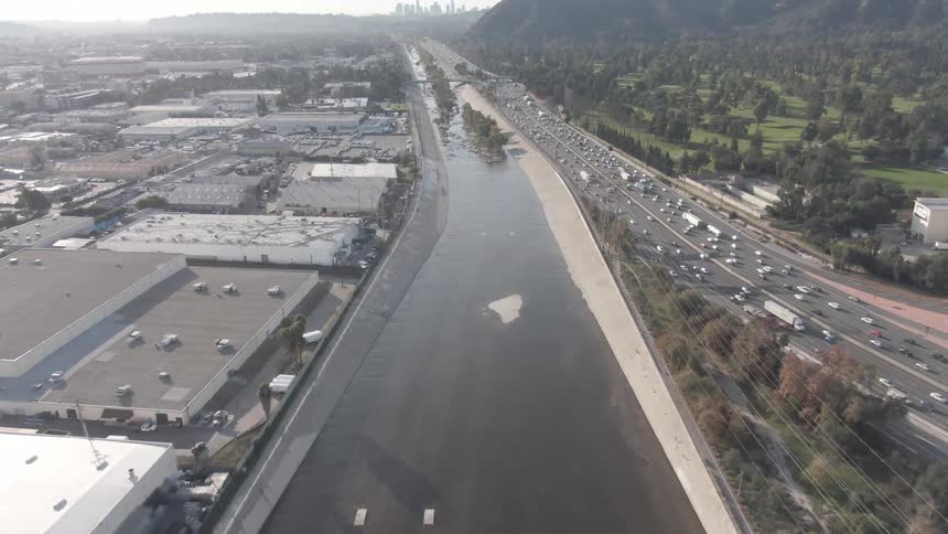 Traffic moves on a highway through a city with a canal