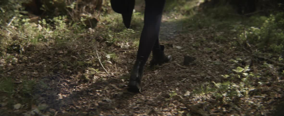 A woman is walking in a wooded area during the day