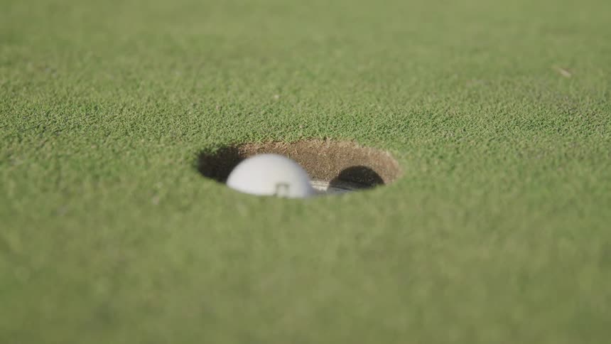 The golf ball lands in the hole