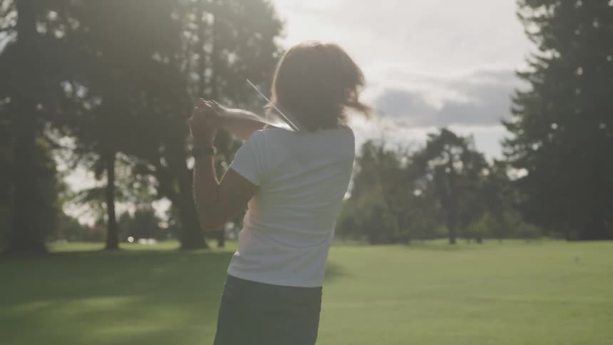 A woman is playing golf outdoors during the summer