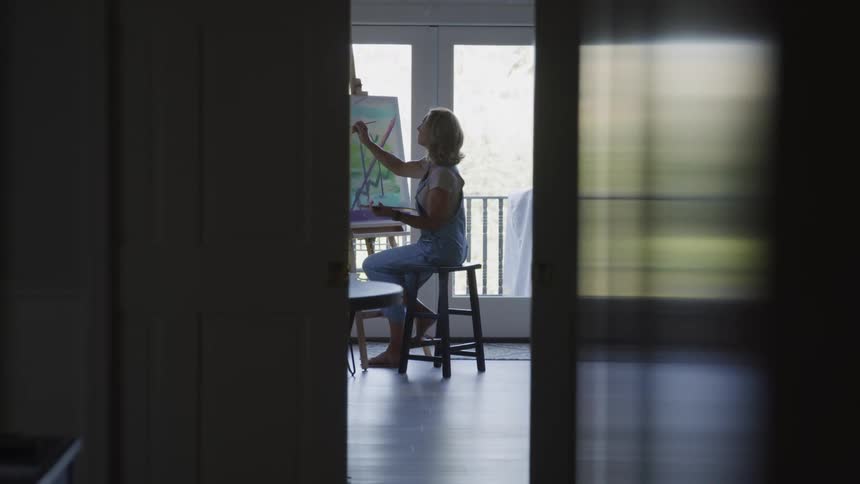 Down the hall a woman is painting on the canvas