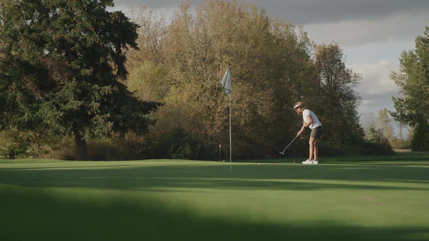 A woman is putting a ball on a golf course