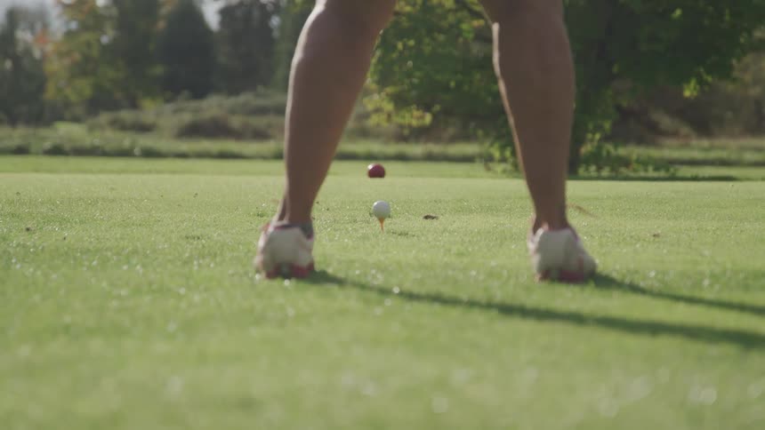 A person takes a golf swing with a driver off a tee