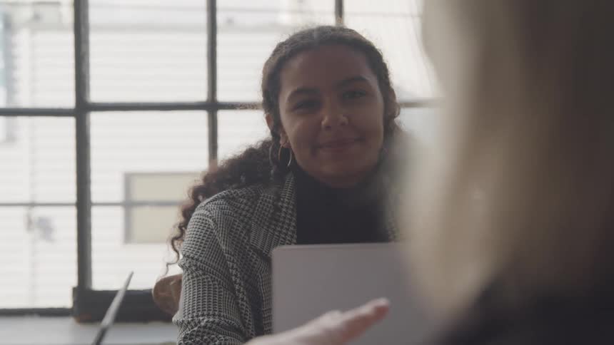 The two woman are sitting across the table from each other talking
