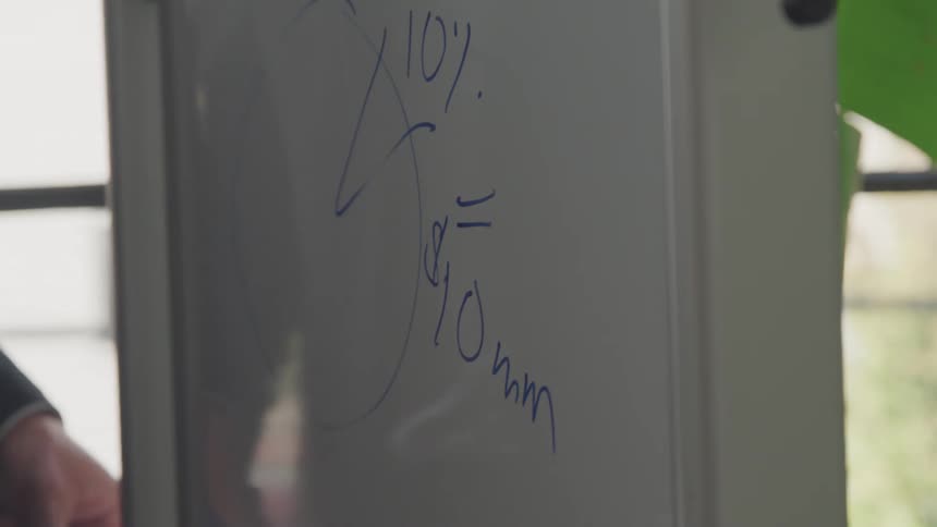 Gentleman in office writing on a blackboard