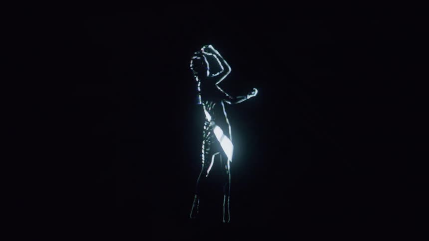 A computerized woman comprised of white bands of light dances slowly