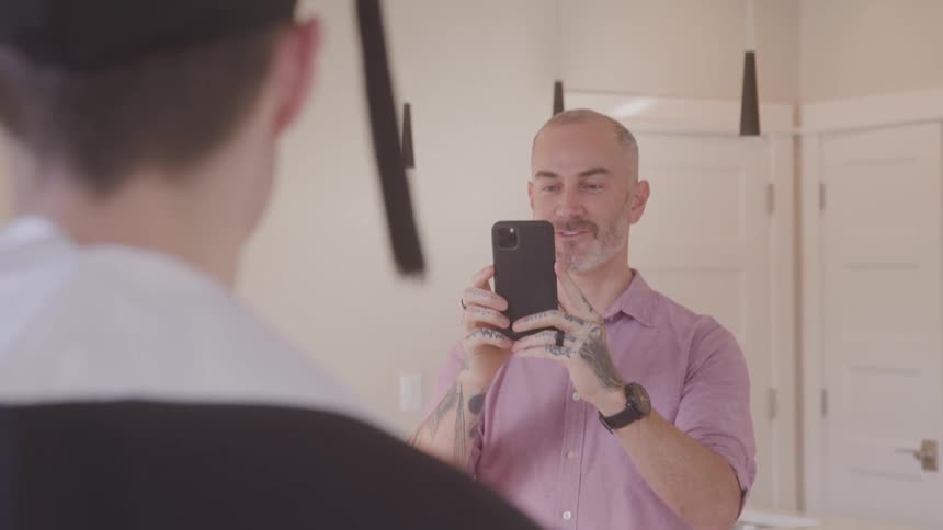 Happy father taking picture of son in cap and gown with cell phone