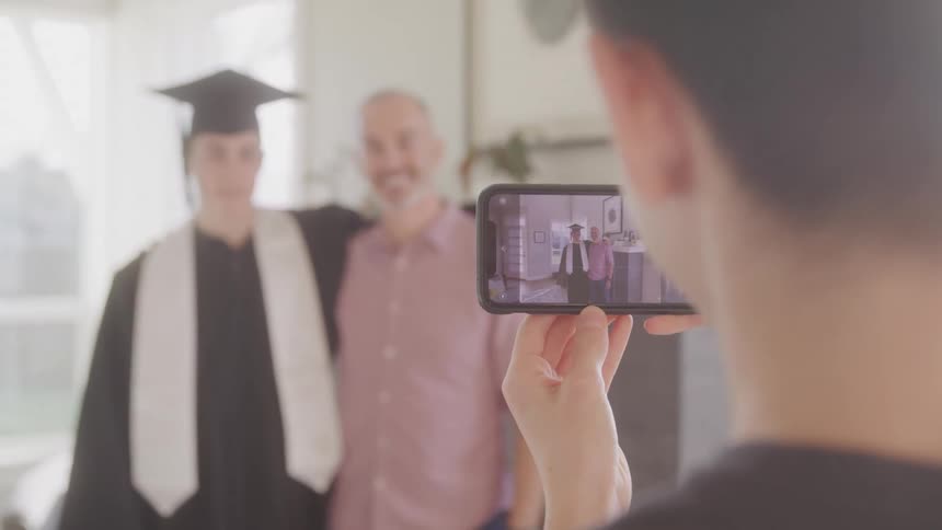 Boy gives a picture to his brother with his graduation robe and his father