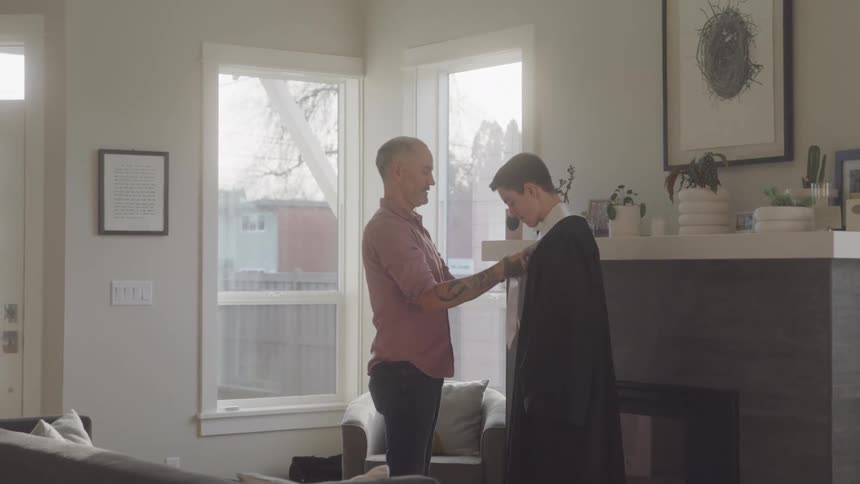 Dad helping to dress son in graduation gown