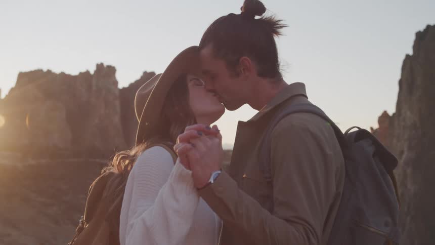 A couple hold hands and kiss