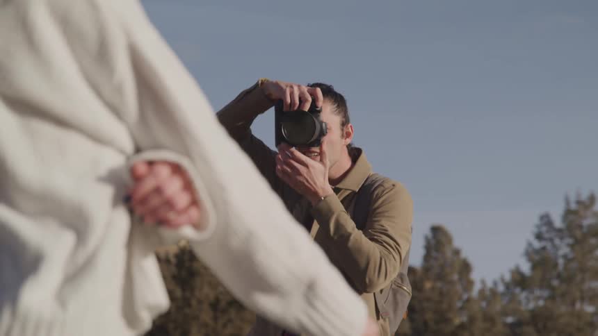 A man is photographing a woman by the mountain
