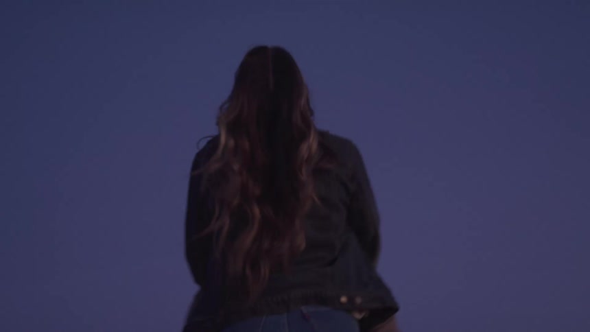 One person lifts another in a joyful embrace silhouetted against a twilight sky