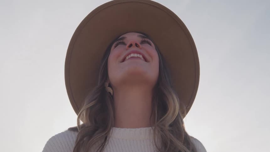A woman is smiling while looking up at the sky