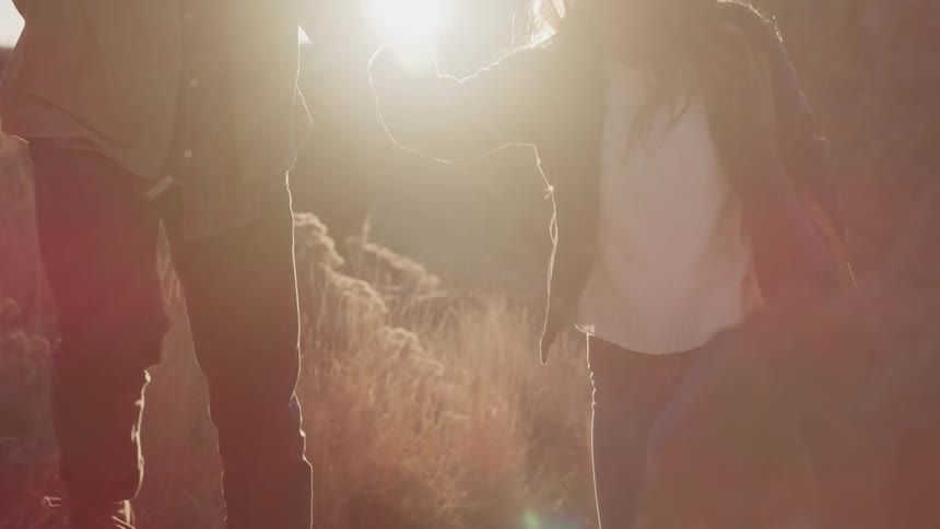 Man helps a woman hike up the mountain under a scorching sun