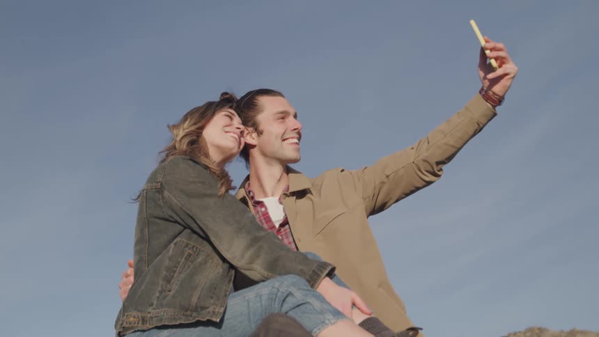 Happy couple taking a selfie with cell phone outdoors