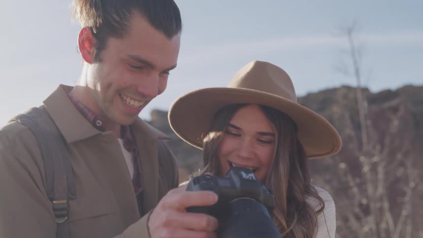 A man and woman look at photos on their camera